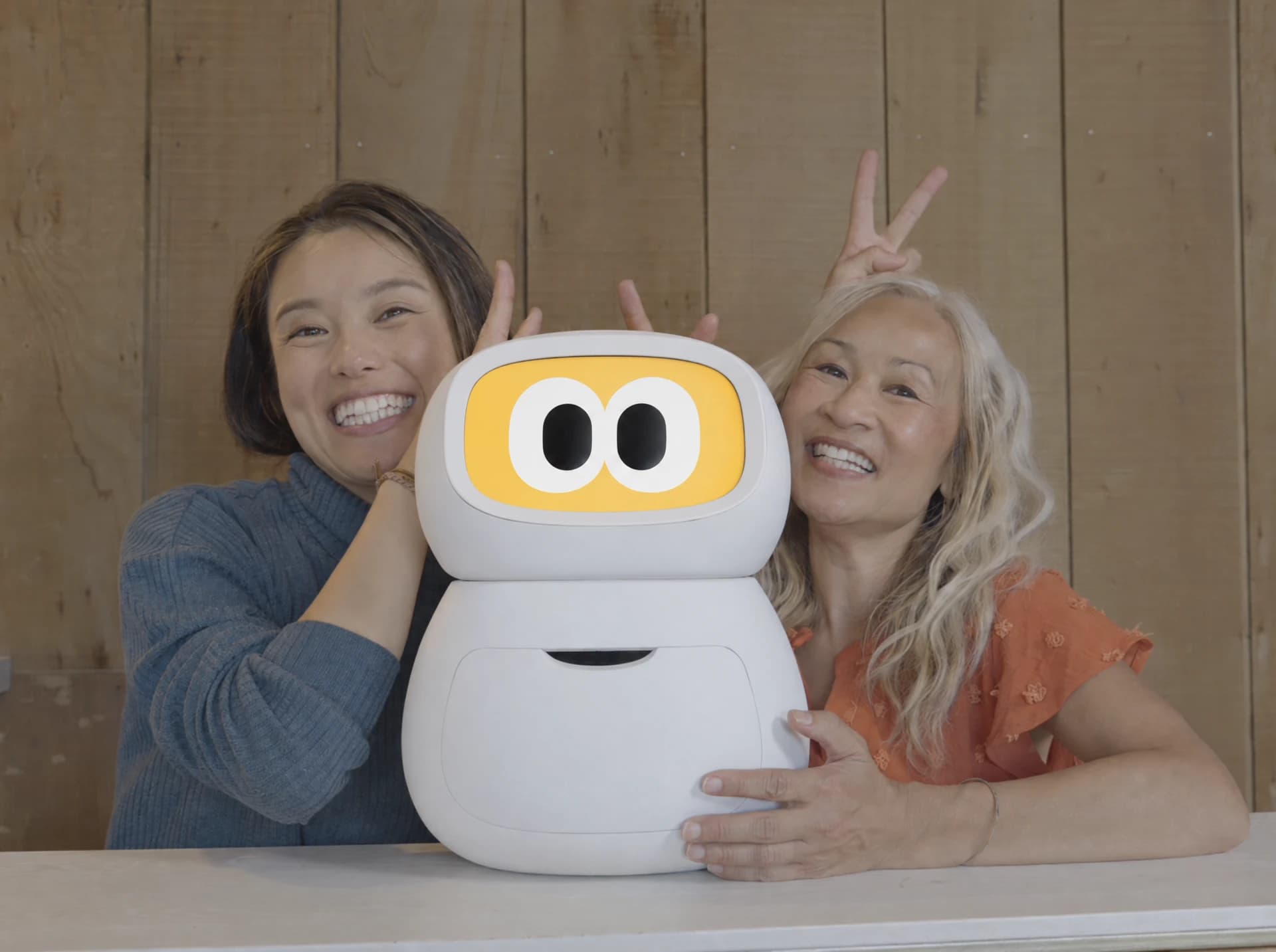Two smiling women posing with the Rhem companion robot